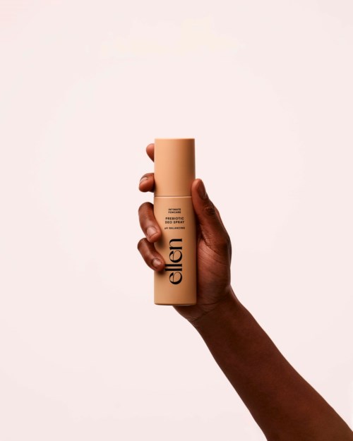 En hand håller en beige flaska med märket 'Ellen'.