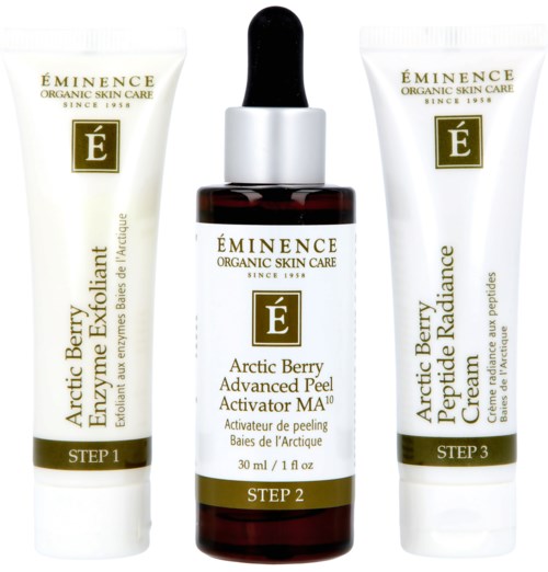 Tre hudpleieprodukter i hvite og mørke flasker med gullmerker for Arctic Berry peel, lotion og krem.