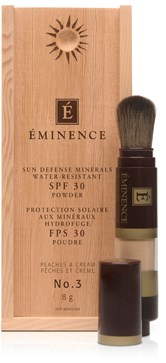 En liten borste och träbox för Eminence solskyddspuder med SPF 30 och persikodoft.