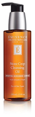 Een bruine fles met labeled Éminence Stone Crop Cleasing Oil. Het heeft een zwarte pomp en een zilveren dop.