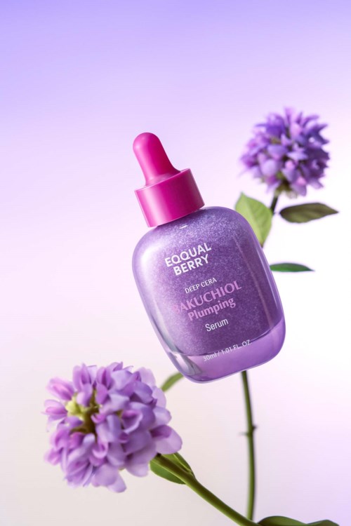A purple serum bottle with a pink dropper cap, two purple flowers, and a purple background.