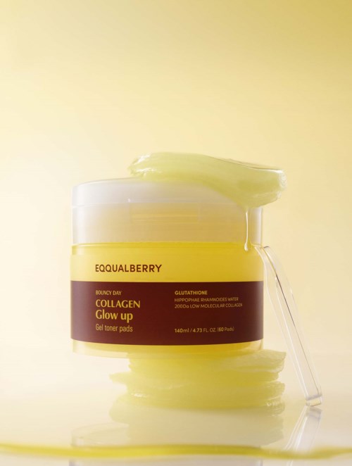En gul krukke med kollagen glow-up gel toner pads, med litt gel på toppen og en skje som ligger mot krukken.