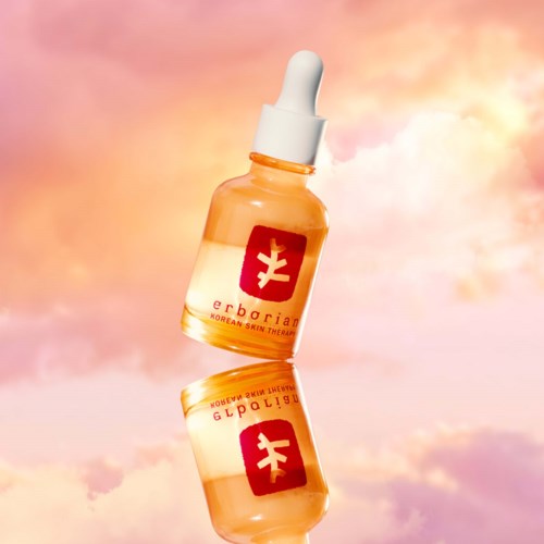 Kleine Glasflasche mit Tropfer, enthält hell gefärbte Flüssigkeit, reflektiert am Himmel.