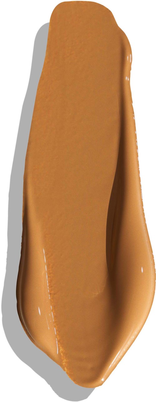 En ske med karamel, glansfuld og glat, på hvid baggrund.
