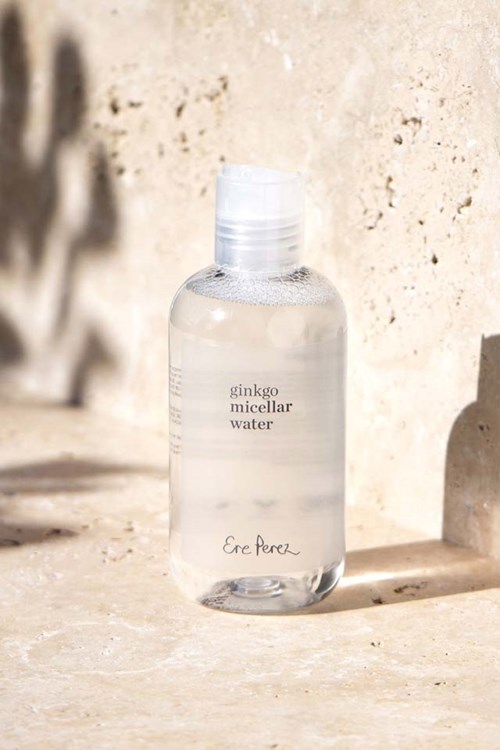 En klar flaska märkta "ginkgo micellar water" står på en solbelyst yta med skuggor bakom.