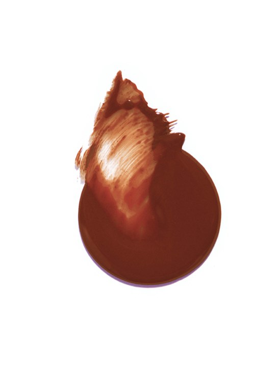 En droppe av brunt flytande, troligen kaffe eller choklad, med stänk på vit bakgrund.