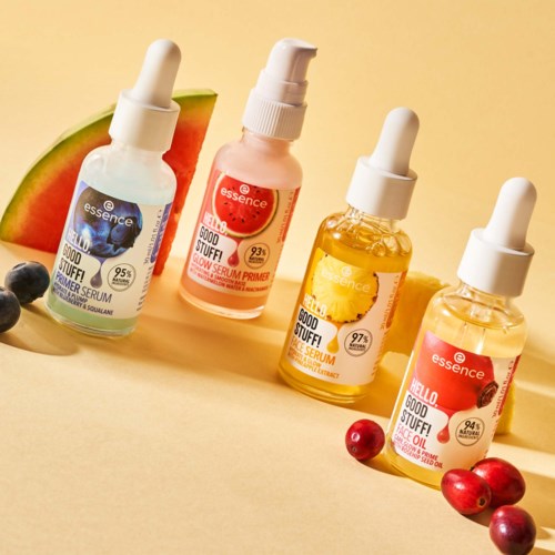 Four bottles of facial serum with fruit images, surrounded by small fruits like watermelon, blueberries, and cherries.