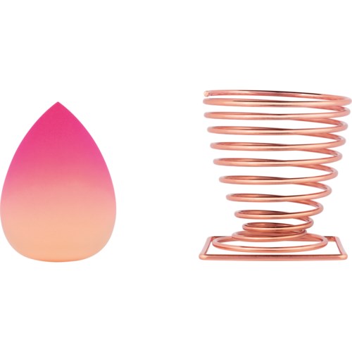 A pink makeup sponge and a pink metal stand shaped like a spiral with a square base.