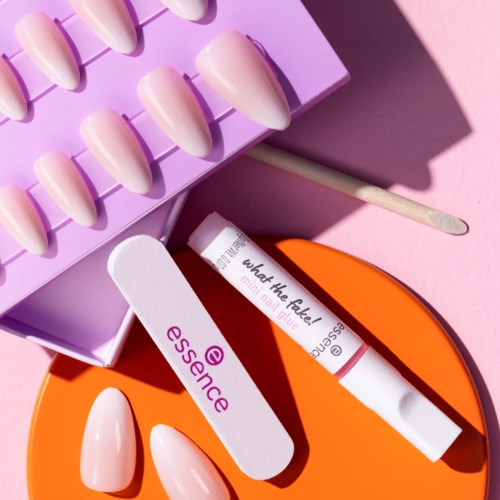 Nagellack och verktyg är organiserade på en rosa yta med en lila förvaringslåda och ett orange fall.