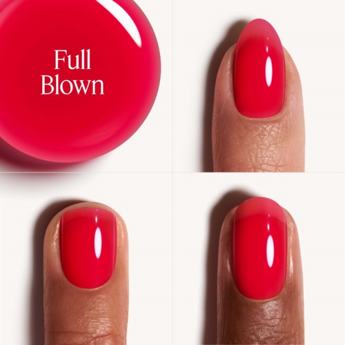 Eine rote Nagellackflasche neben drei Fingern mit roten Nägeln.