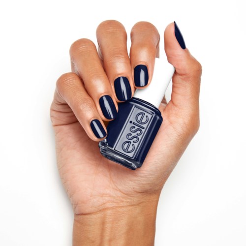 En hand med blå naglar håller en liten flaska med blå nagellack märkt 'essie'.