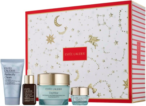 En festlig Estée Lauder hudvårdsset med krämer, serum och en liten burk, dekorerad med guldstjärnor, månar och en ängel.