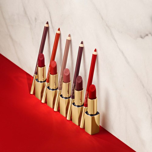 Lipsticks in een rij met verschillende tinten, van rood tot roze, op een rode en witte achtergrond.