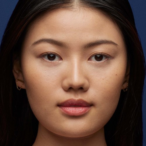 A young woman with long dark hair, clear skin, and minimal makeup, looking directly at the camera.