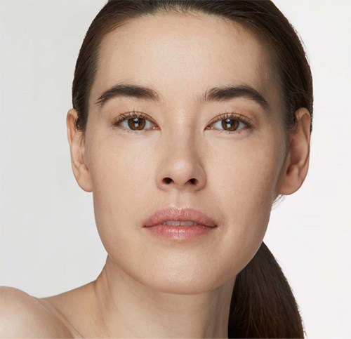 A woman with clear skin and brown hair, looking directly at the camera with a neutral expression.