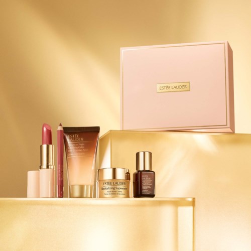 Estée Lauder hud- och makeupprodukter på en gyllene yta med en rosa box i bakgrunden.