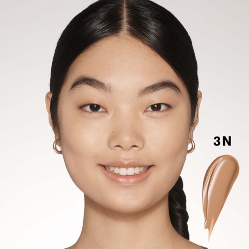 En kvinna med svart hår ler, med en 3N makeupprodukt i brunt på kinden.