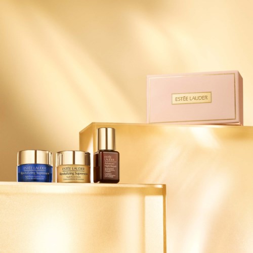 Estée Lauder hudvårdsprodukter på en guldig hylla med en rosa Estée Lauder-ask i bakgrunden.