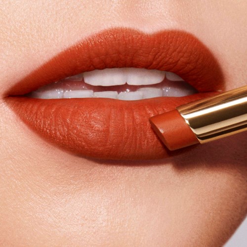 Close-up van lippen met bruin lippenstift en deel van gouden lippenstiftdoos.