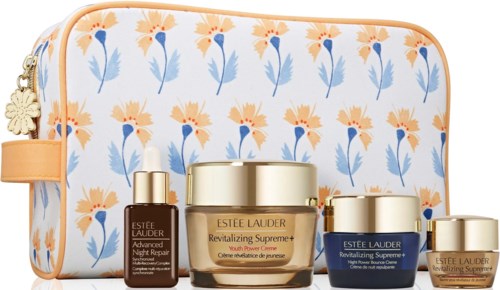 Zestaw produktów pielęgnacyjnych Estée Lauder z pomarańczowymi, niebieskimi i złotymi opakowaniami, na tle torby z kwiatami.