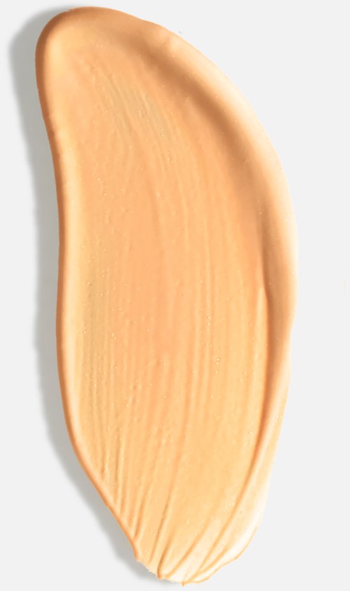 En smorda beige- eller persikofärgad makeup eller kräm på en vit bakgrund.
