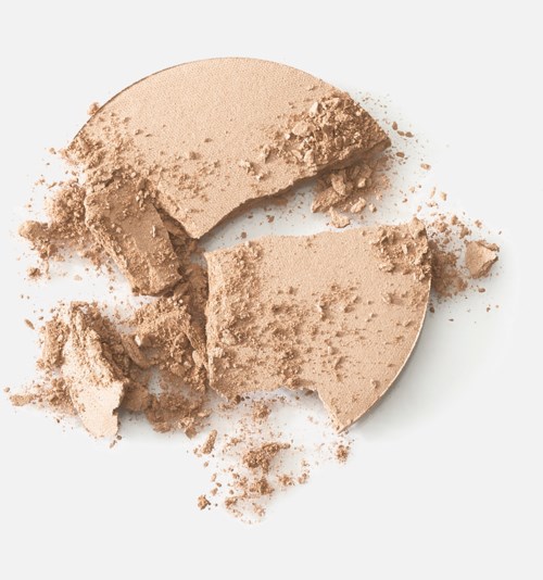 Krossad beige puder, troligen foundation eller ansiktspuder, på vit bakgrund.
