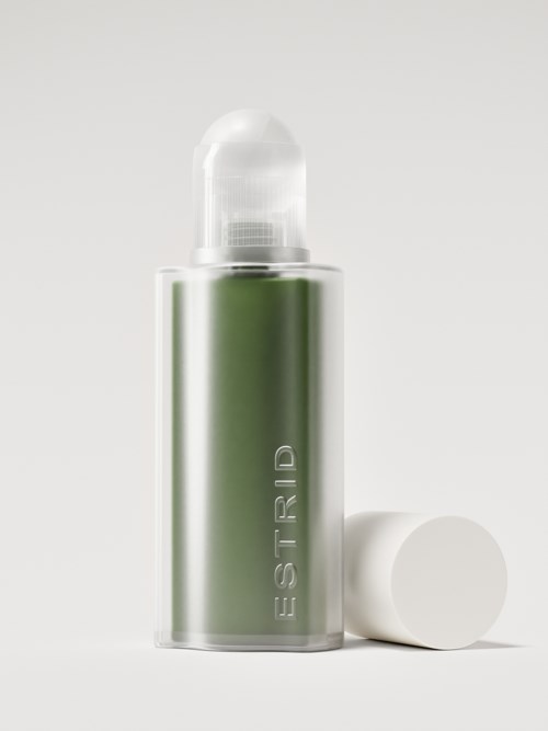 En grön sprayflaska med vit kork, står upprätt med korken av. Enkel och ren design.