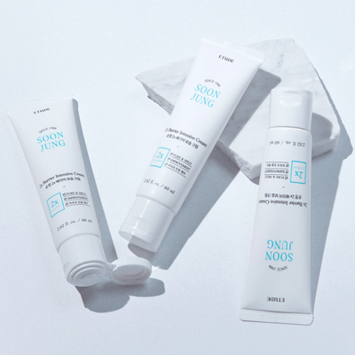 Zwei Tuben Hautpflegecreme und eine Flasche liegen auf weißer Oberfläche, mit hauptsächlich blauer und schwarzer Schrift.
