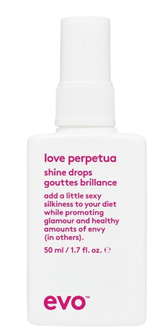 Flesje van Love Perpetua Shine Drops met roze tekst en witte pomp, promoot een glamoureus, sexy huidverzorgingsproduct.