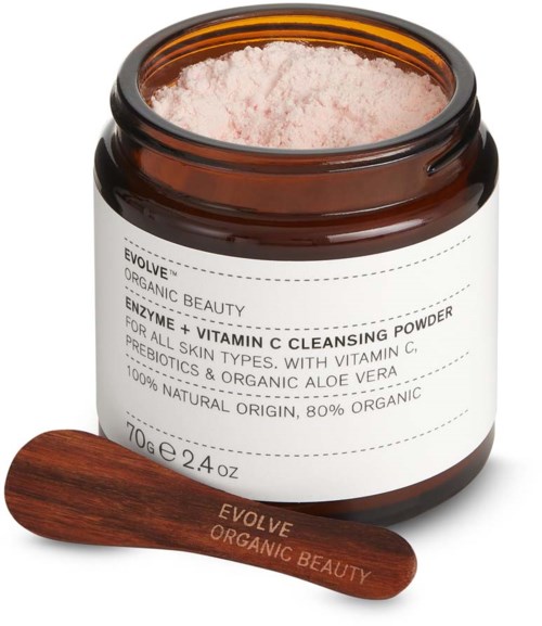 En åben beholder med lyserødt pulver og en træske ved siden af, mærket 'Evolve Organic Beauty' med vitaminer og økologiske ingredienser.