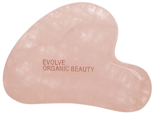 Vaaleanpunainen sydämen muotoinen gua sha -työkalu, jossa lukee 'EVOLVE ORGANIC BEAUTY'.