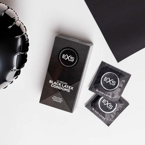 Svart latex kondomförpackning med två kondomer och en svart folieballong i närheten.