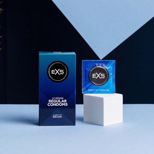 En ask och ett kondomförpackning med märket EXSs på en vit stång mot en mörk och blå bakgrund.