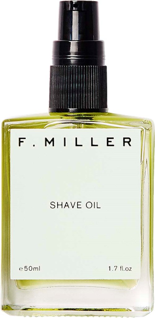 A transparent spray bottle with a black cap, labeled 'F. Miller Shave Oil,' containing greenish liquid.