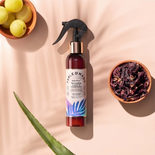 A brown spray bottle with a black trigger and white label, surrounded by yellow grapes and dried purple flowers.