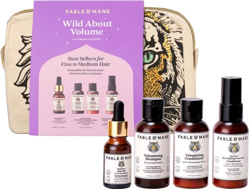 Set of four small brown bottles of hair care products with black caps, placed in front of a beige bag with a tiger illustration and a purple leaflet.