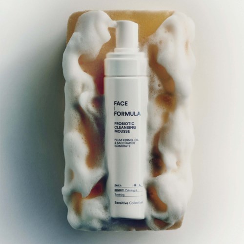 Een witte fles met Label Face Formula Probiotic Cleansing Mousse omgeven door schuim in een doos.