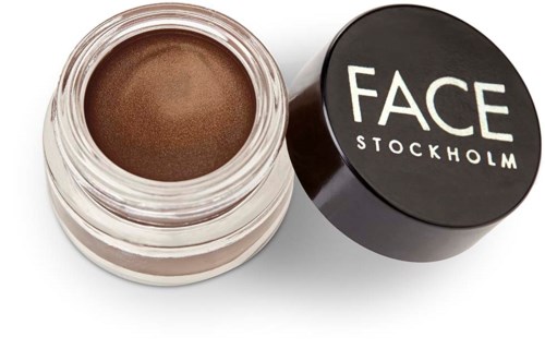 Ein kleiner Behälter mit braunem Gesichtsmakeup und schwarzem Deckel mit der Aufschrift 'FACE STOCKHOLM'.