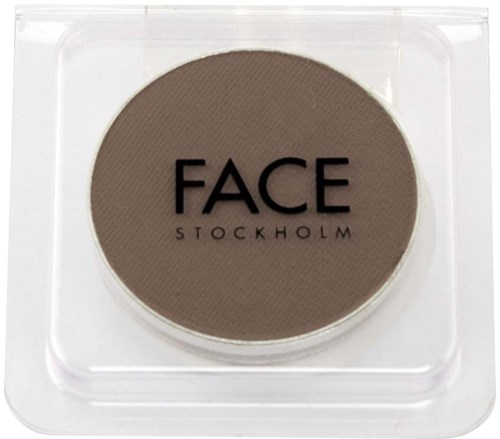 Ett runt, brunt sminkprodukt med orden "FACE STOCKHOLM" på, i ett plastbehållare.