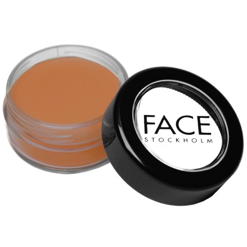En liten rund behållare med ansiktsmakeup eller concealer med svart lock märkt 'FACE STOCKHOLM.'
