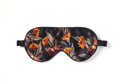 En sömnmask med svart bakgrund och färgglad blomsterdesign, inklusive orange, röda och gröna blommor och blad.