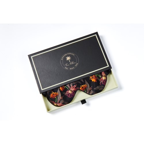 Ett box med ett blommigt band inuti, delvis täckt av ett svart och guld lock.