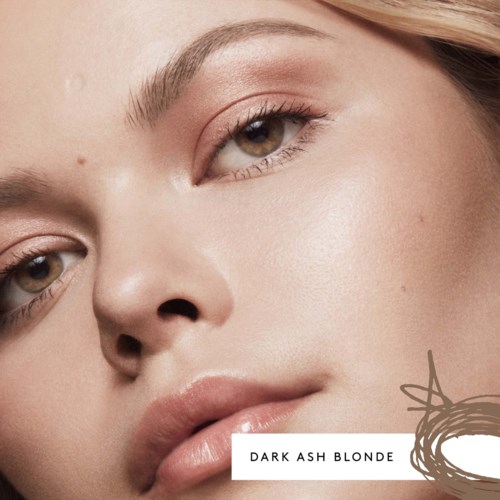 Närbild av en kvinna med ljus hud, blond hår och naturlig makeup, som tittar mjukt mot kameran.