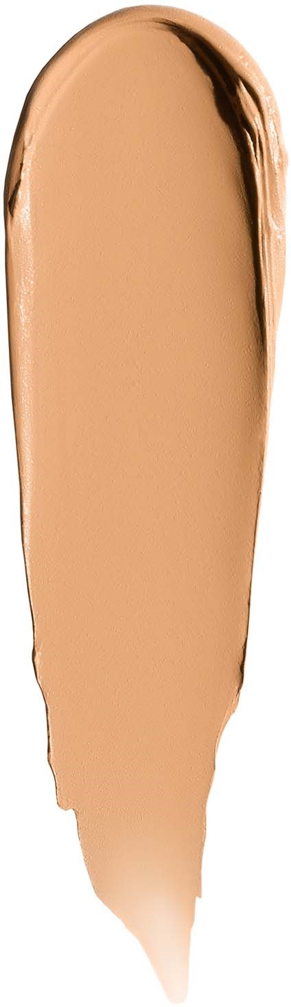 Beigeä näytelääke tai meikkivoide, jossa yläosassa on levitysjälki.