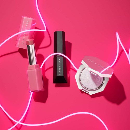 Lipstick, lip gloss, and eyeshadow with pink background and neon lights.