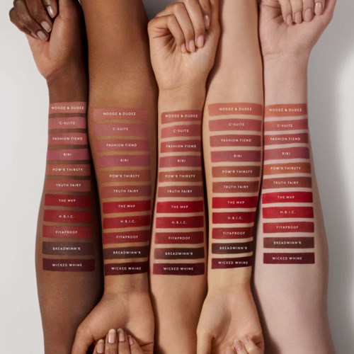 Fyra armar visar swatches av olika läppstiftsnyanser med etiketter på varje strip.