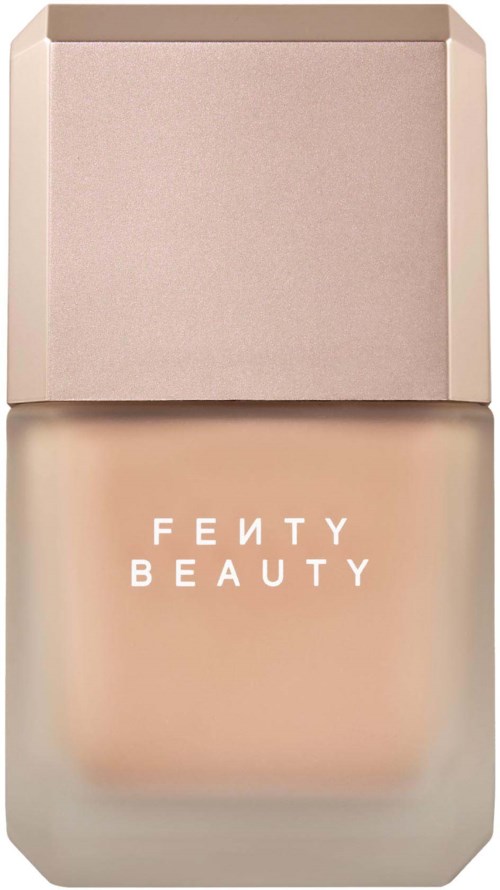 En Fenty Beauty foundationflaska med fyrkantigt, frostad glas och ljus beige vätska.