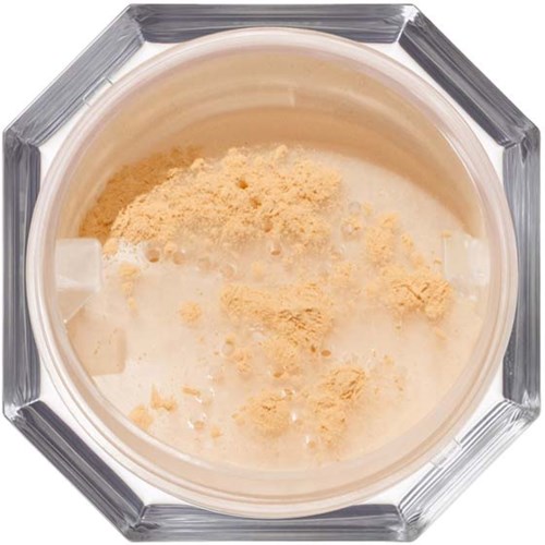 Creamy drink with pudding mix and powder inside a glass. Octagonal glass container. No additional elements visible.