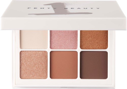 Six eyeshadow pans in a white palette, featuring shades of beige, pink, copper, peach, warm brown, and dark brown.