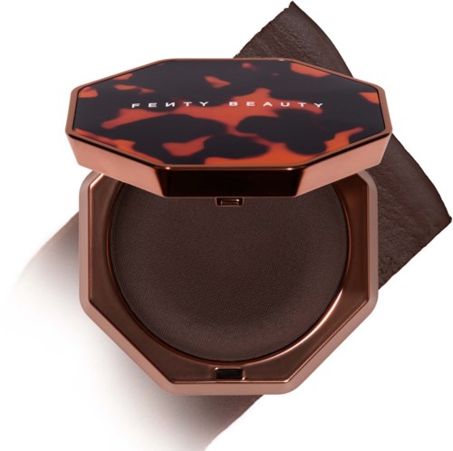 Pyöreä meikkikompakti, jossa on tumma sävy, ja siihen on painettu Fenty Beauty -logo päällä.